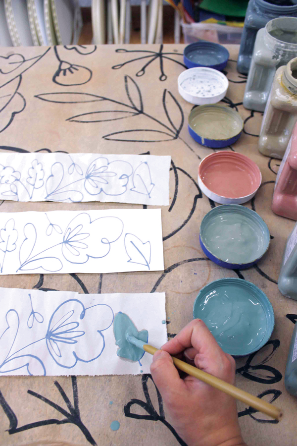 4 Once the underglaze has dried, use colored slip (white slip with Mason stains) to paint in the design on newsprint.