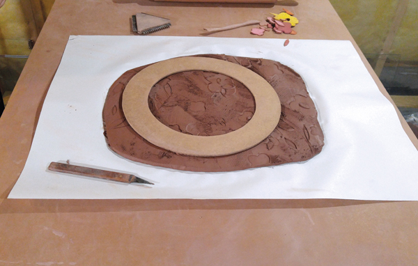 4 Cutting out the plate shape using the rim of the two-part Masonite template as a guide.