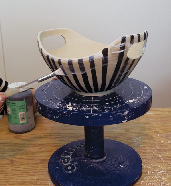 7 Continue painting vertical stripes around the form. After the underglaze dries to the touch, apply a coat of wax resist to the exterior.