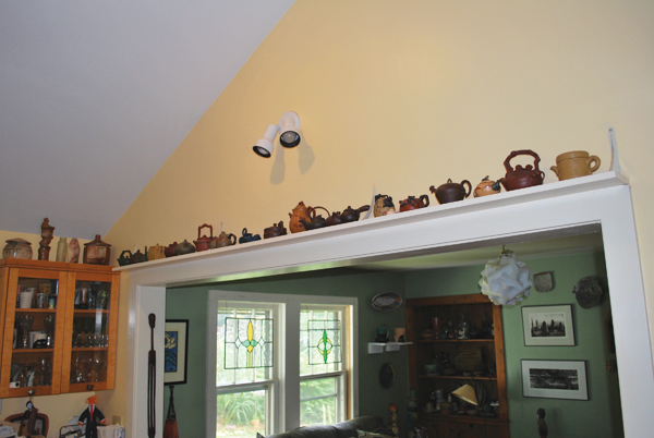 11 Yixing teapot collection displayed on shelving over entryway into the family room.