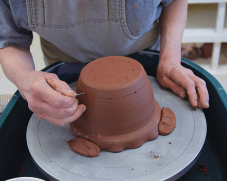 8 When the inner pot is leather hard, use the decorating disk to mark a pattern of holes in the bottom and sides of the pot.