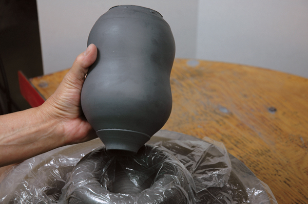 5 Invert the bottle onto a plastic-covered, thrown clay chuck for trimming.