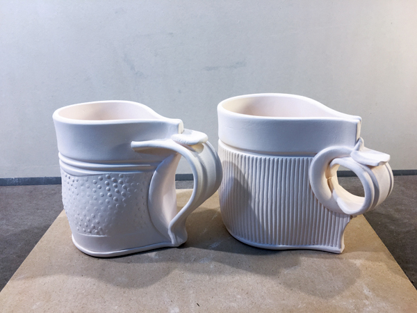 8A Two bisque-fired cups with variations of the basic rolled handle.