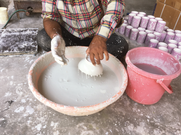 4 Unbisqued ware that has already had underglaze decoration painted on has transparent glaze applied. Rather than dip the piece into the glaze, a worker will splash the glaze on by hand.