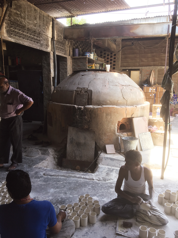 6 Workers seated in front of the kiln. The door to the firebox is seen in front; the only other entry point into the kiln is at the top, which is where the kiln is loaded and unloaded.