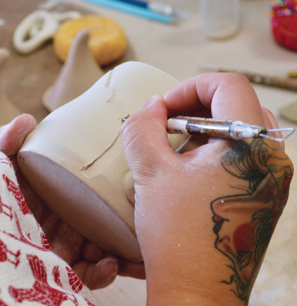 1 Holding a ribbon tool at an angle, slowly carve an angled edge into the pot.