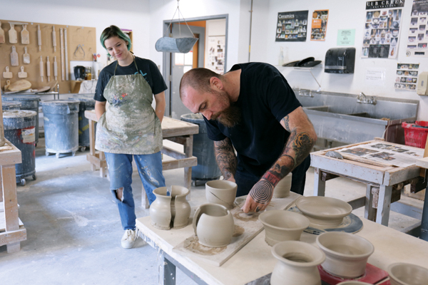 4 A. Blair Clemo cutting student Gabzy Rinker’s pots into two pieces. Photo: Samuel Brown. 