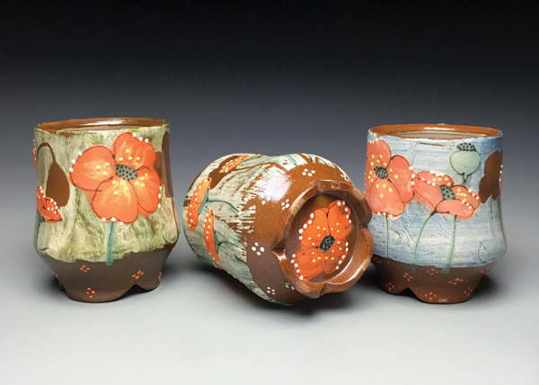 Three cups with cut feet, wheel-thrown and altered red clay, slip, glaze, soda fired to cone 1 in a gas kiln.