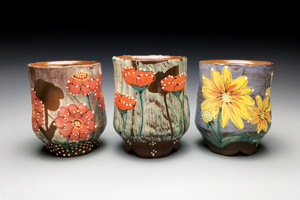 Three cups with cut feet, wheel-thrown and altered red clay, slip, glaze, soda fired to cone 1 in a gas kiln.