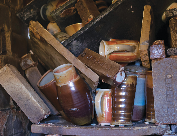 2 After: Squished, fused-together pots in a toppled kiln stack caused by a shelf break- ing under the weight of the offset posts.