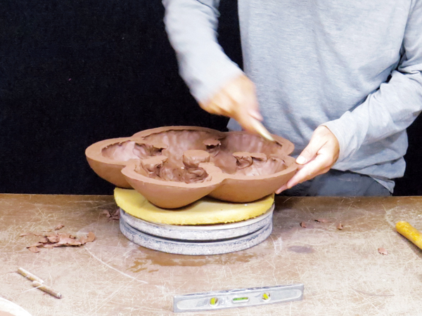 4 Flip the leather-hard platter mold over onto a piece of foam, remove the clay supports, and smooth the interior.