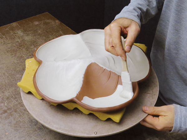 10 After the textured slip dries, apply white slip over top to create contrast with the darker clay rim and bottom of the platter.