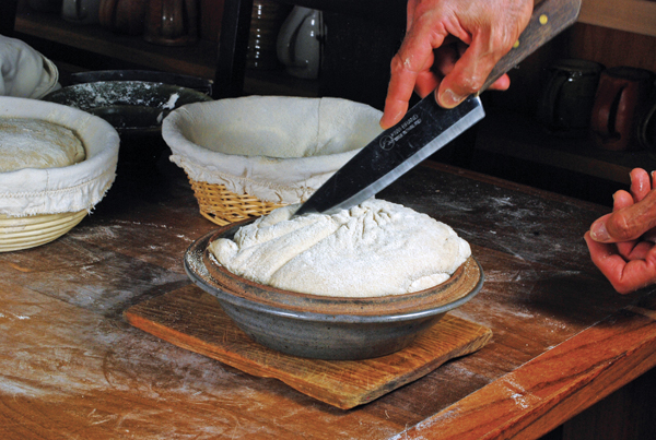 17 Score the loaf after inverting it into the hot cloche, cover, and bake it.