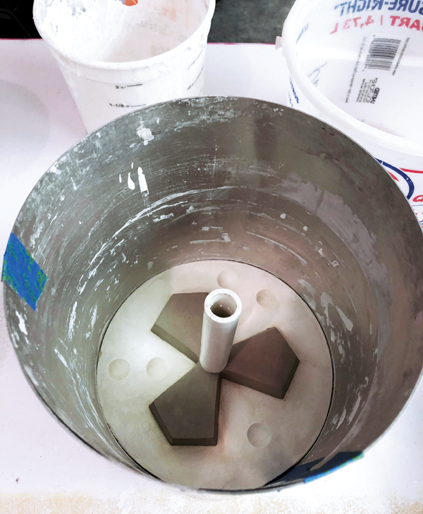 8 Place a PVC pipe in the back of the tile form to create a pour hole. Use aluminum flashing to contain the plaster when pouring it onto the first mold part.