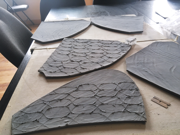 4 Leather-hard slabs with green glaze and scored with an X-Acto knife, which will be once-fired and gently tapped on the back side with a hammer to separate the individual tiles.