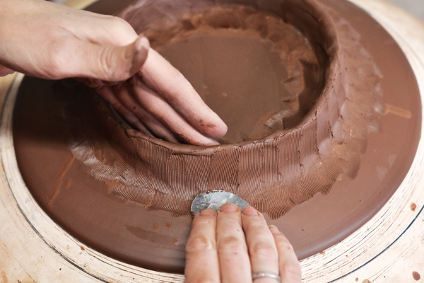 5 Using a serrated rib, move clay from the foot ring onto the body, making a seamless connection. Smooth away the marks.