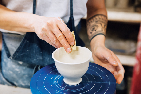 5 As the banding wheel spins, use a wet chamois to apply soft, even pressure to give a round edge to the rim of the cup.