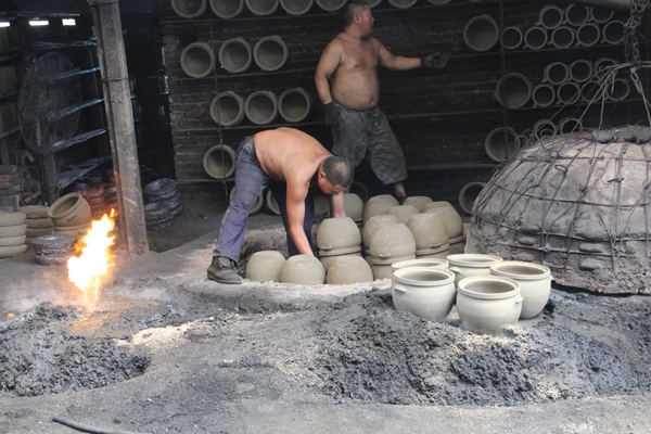 3 Loading warmed pots onto clay chucks for the next firing. A layer of coal has already been spread onto chamber’s floor.