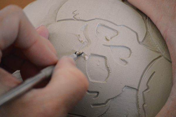 6 Begin to define the middle ground of the carving by removing clay and adding detail.