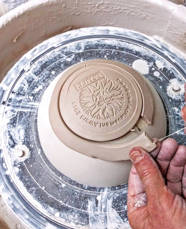 2 Trim away the extra clay once the logo has been centered on the wheel and the drape mold.