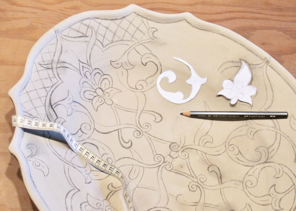 1 The initial design is drawn freehand and by tracing cut-out paper design elements using a soft 4B pencil on the leather-hard slip.