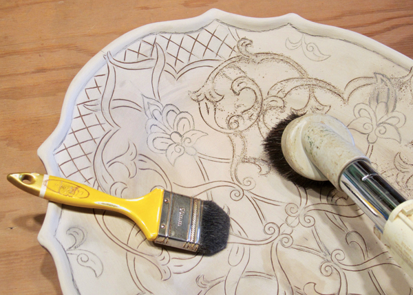 3 A brush and a vacuum with a brush attachment are used to remove the burrs created by the sgraffito process from the piece. 