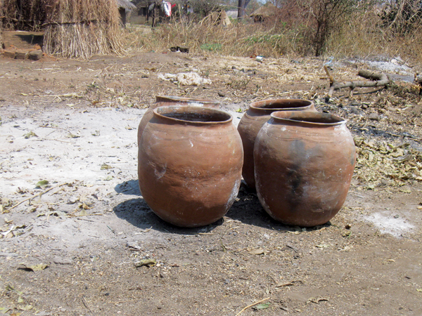 4 Four large coil-formed pots sitting in the ashes from a recent firing. Eness leaves the pots in the ashes to discourage curious elephants from stomping on them. 