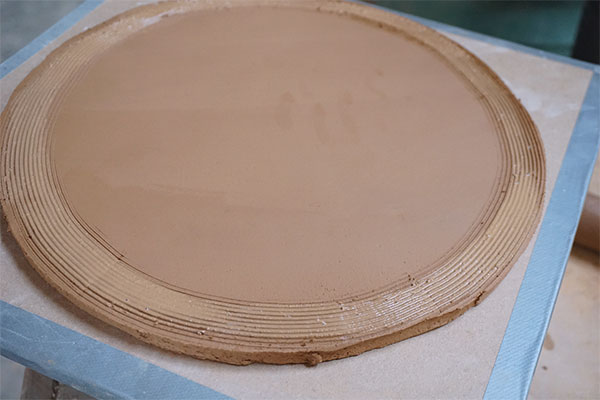 1 Cut out a circle from a compressed slab, put it on a ware board, then score and slip the outside top edge.