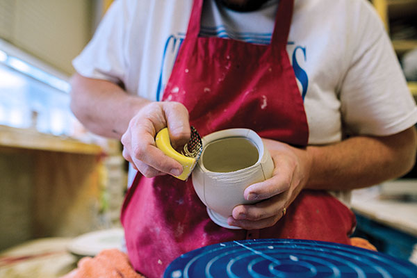 8 Carefully remove clay from the surface with a Surform near the rim of the cup and the stand to create matching squared-off forms.