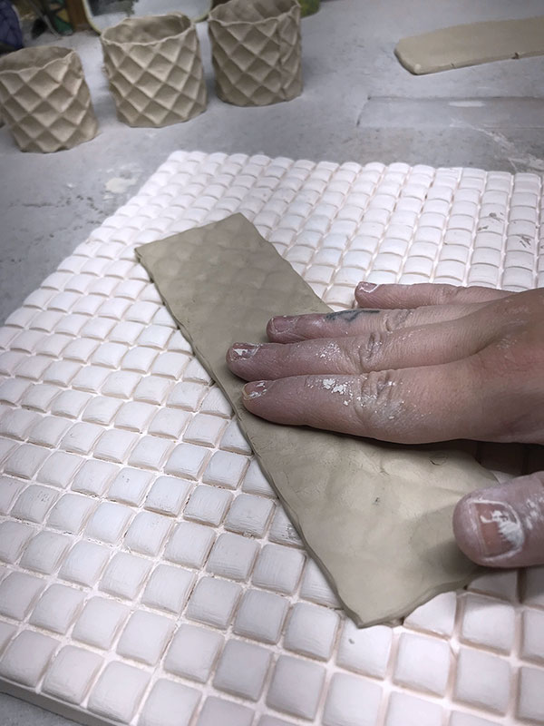 3 Press the soft slab into the waffle cone bisque mold then form into a cylinder.