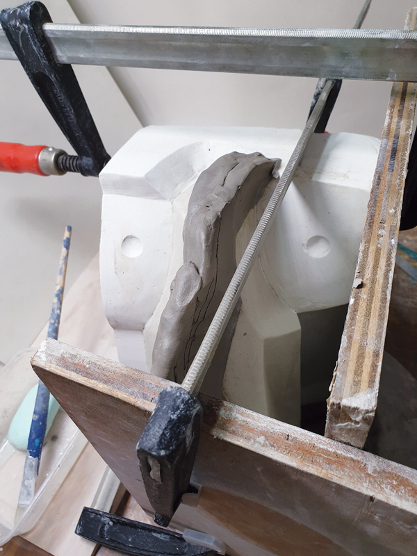 10 Brush five layers of olive oil or mold soap on to the first plaster section as a separator. Next, build a slab partition along the next parting line that has been determined. Set up the cottle boards and secure with clamps, then pour the plaster to create the second section.