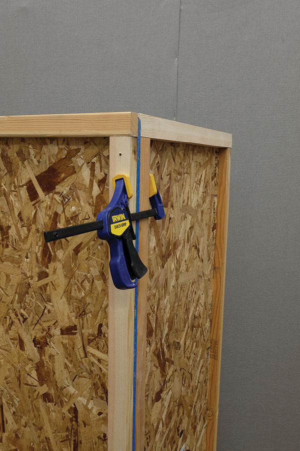 2 Use a clamp to hold the framed panels in place while securing the first two walls together and then to the base.