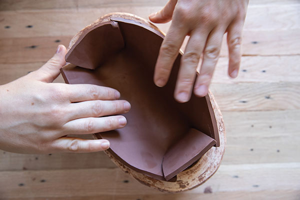 3 Score and add slip to the darted edges of the slab, then press it into the lid mold.