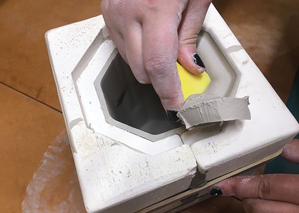 2 Use a stiff rubber rib to cut away excess clay from the mold gallery.