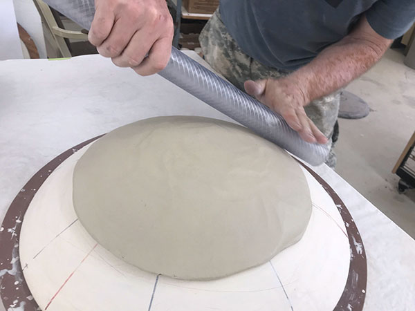 1 Bisque fire a clay hump mold. Place a slab over the mold. Compress and thin the slab using a length of flexible plastic tubing. 