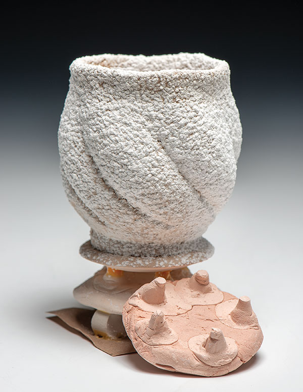 1 Bisque-fired cup, glazed, frit dusted. Shown prior to the glaze firing, as it would be loaded into the kiln. An extra pot sitter is placed in front of the cup to show the points of contact that support the cups.