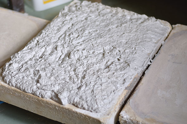 2 Spread out a layer of the fiber-clay slurry on slabs of plaster to dry it to a workable consistency. 