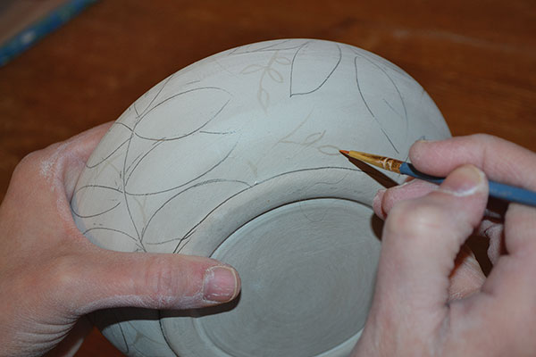10 Draw leaves onto the sides and the wide flat rim, then brush on wax leaves.