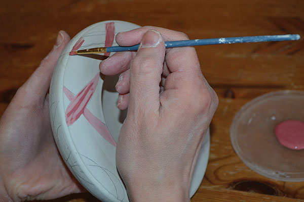 11 Brush underglaze into the ribbon shapes on the wide top rim.