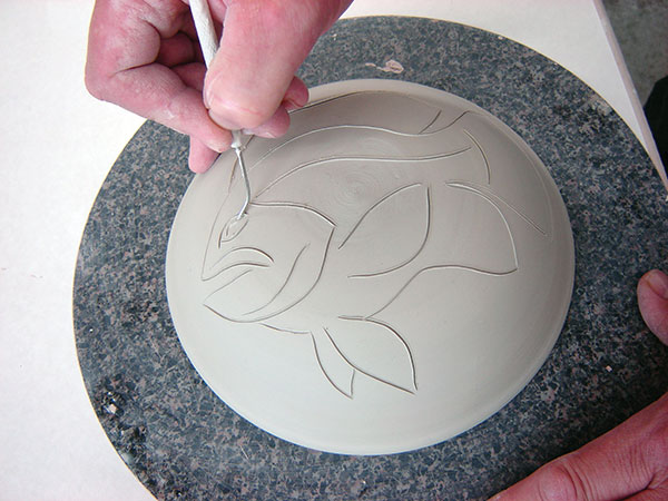 3 Drag the bent tip of the needle tool over the clay to sketch a design. 