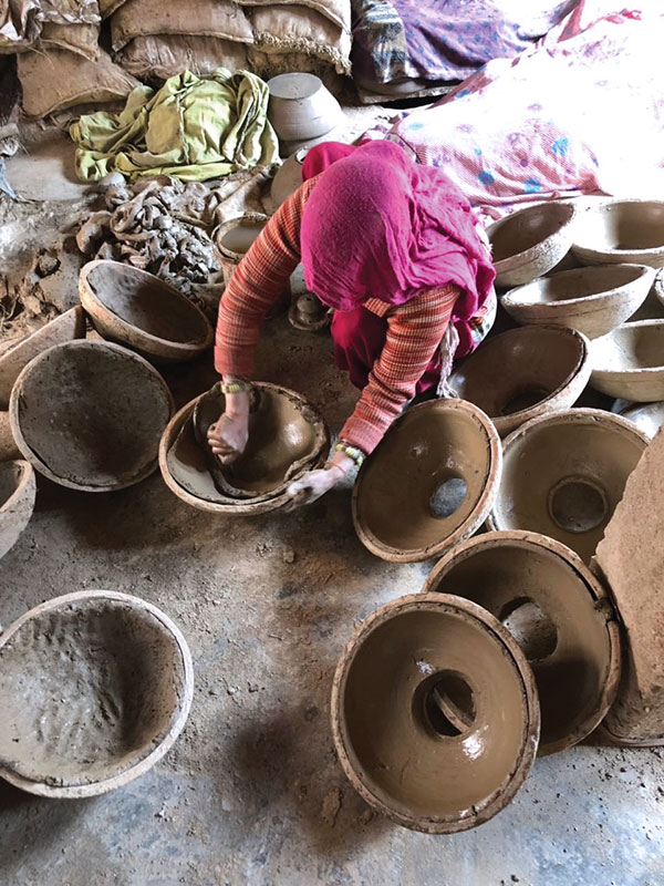 4 The potter cuts through the center of the slab in the press mold and removes clay to create the neck opening.