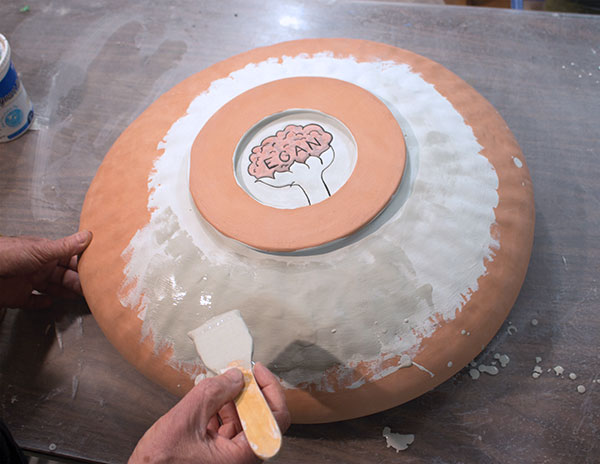 8 Paint the back of the plate with a flowing matte glaze once the front and interior of the foot ring are complete. 