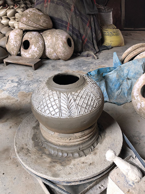 10 After the jar is removed from the press mold, it is centered on the wheel, supported by a bisque-fired chuck. The relief area on the shoulder of the pot is dusted with mica from when the disk of clay was formed on the ground before being placed in the mold.