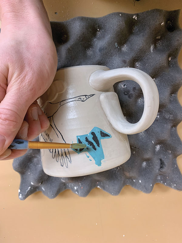 10 Brush the crumbs away, then paint various colors of underglaze into the carved details.