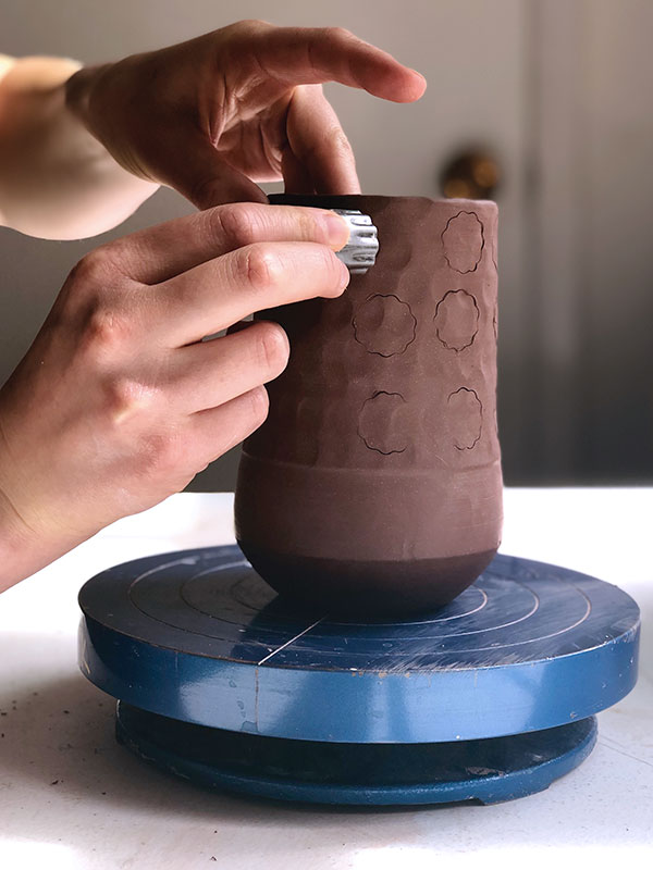 3 Starting at the lip, apply a pattern by pressing a metal cookie cutter into the clay.