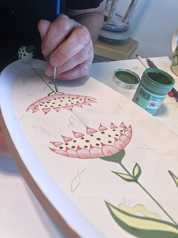 11 Paint the stems and leaves of the flowers next, applying the lighter color first.