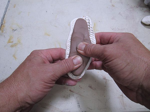 7 Press wet clay slabs into small molds to create sections for the teapot.