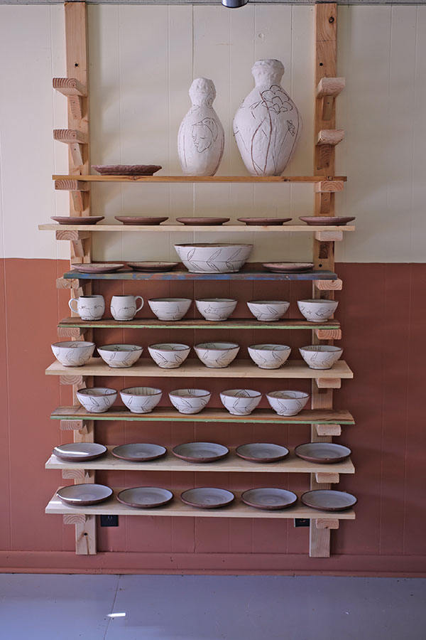 Flexibility with this shelving unit comes from placing shelves on every arm brace or skipping a few braces between shelves to accommodate taller pots, creating a space-saving shelving unit with ware boards that can be removed to transport pottery. 