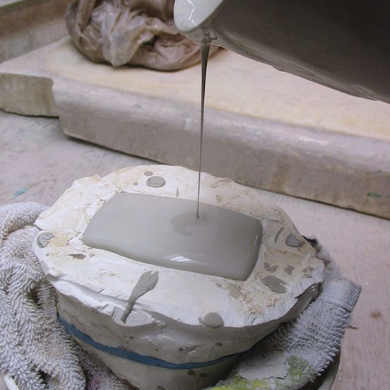 4 After refining the mold and allowing it to dry, reassemble and secure it, then pour in casting slip.