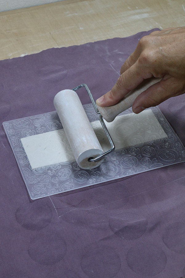 3 Roll a brayer on the back of the plastic to transfer the texture. Peel the slab off to reveal the texture.